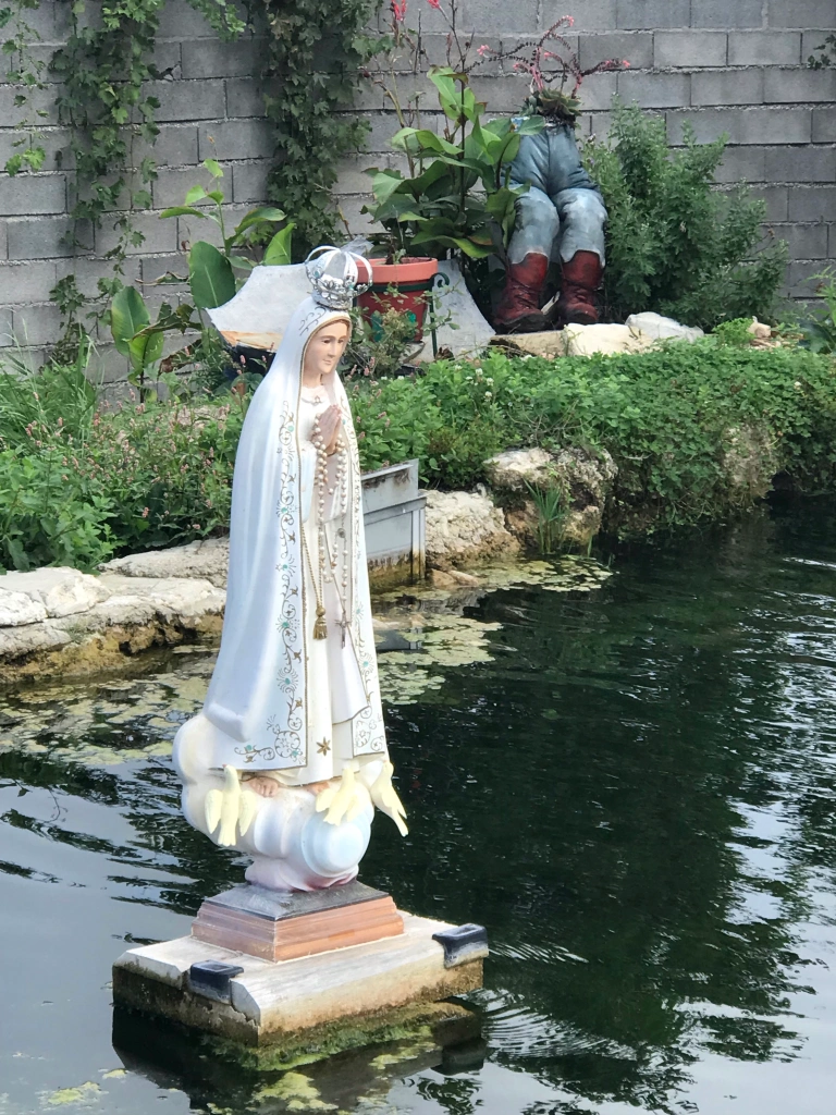 Fatima icon in pond with stuffed jean planter